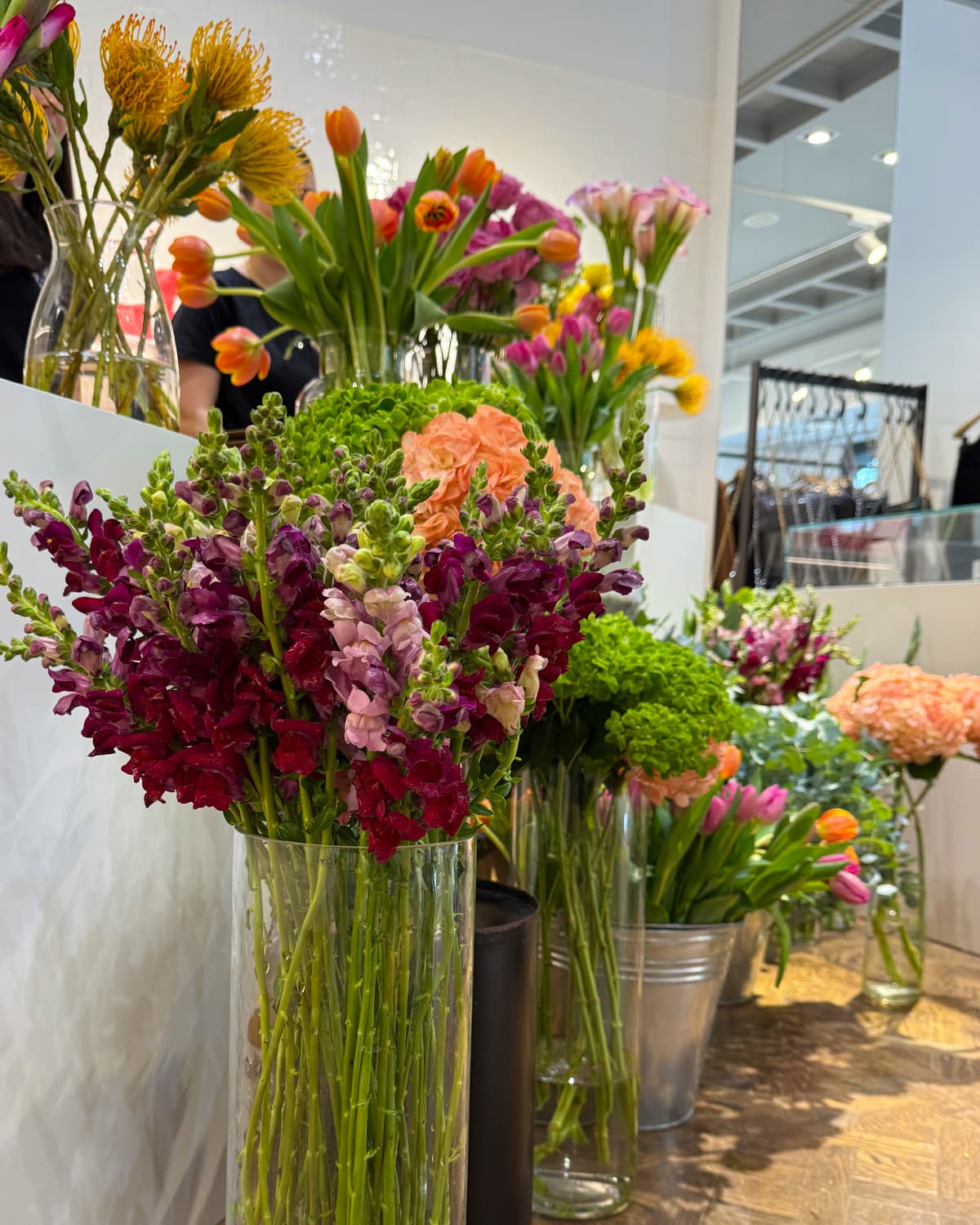 barra floral premium con flores frescas de temporada, recipientes elegantes y presentación editorial, en un evento cuidado y luminoso.