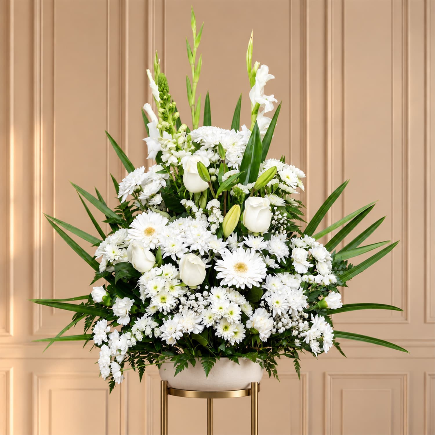 Centro floral funerario en forma piramidal con rosas, gerberas, gladiolos y crispantemos blancos con follaje verde.