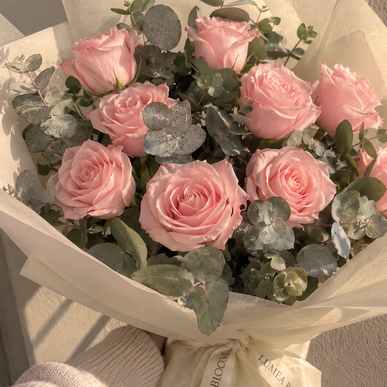 Ramo de rosas rojas naturales con verdes decorativos en envoltorio de papel kraft