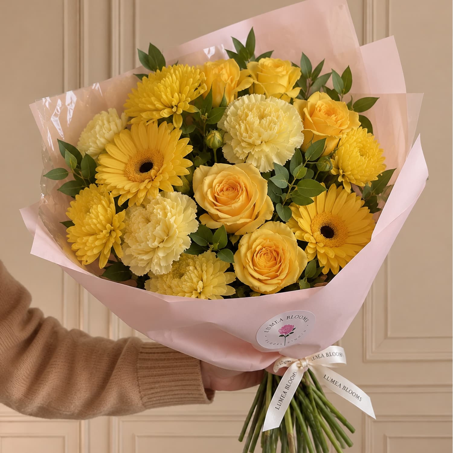 Ramo de flores amarillas con rosas, claveles, gerberas, crisantemos y paniculata envuelto en papel de regalo.