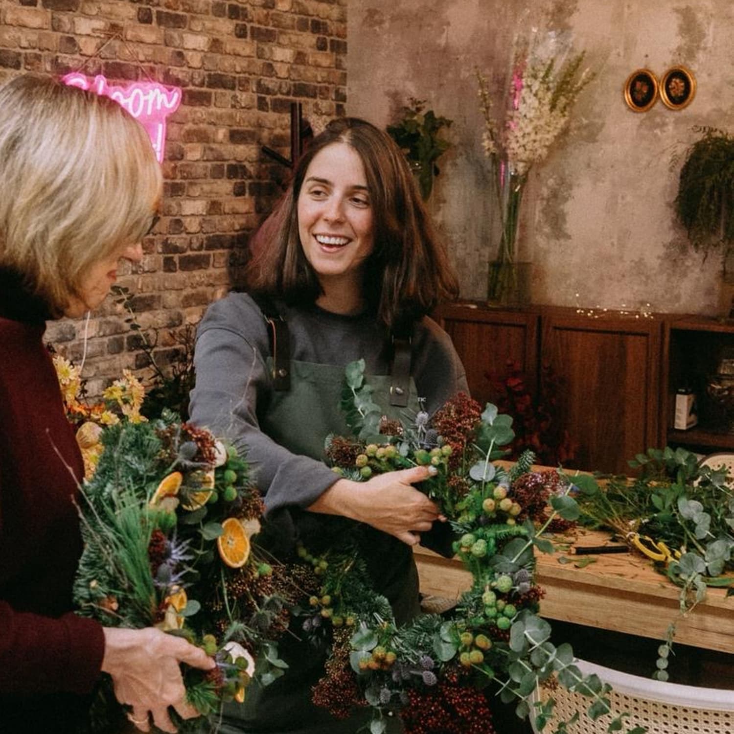Florista guiando paso a paso a una alumna a equilibrar los volúmenes y el movimiento de su centro de mesa.
