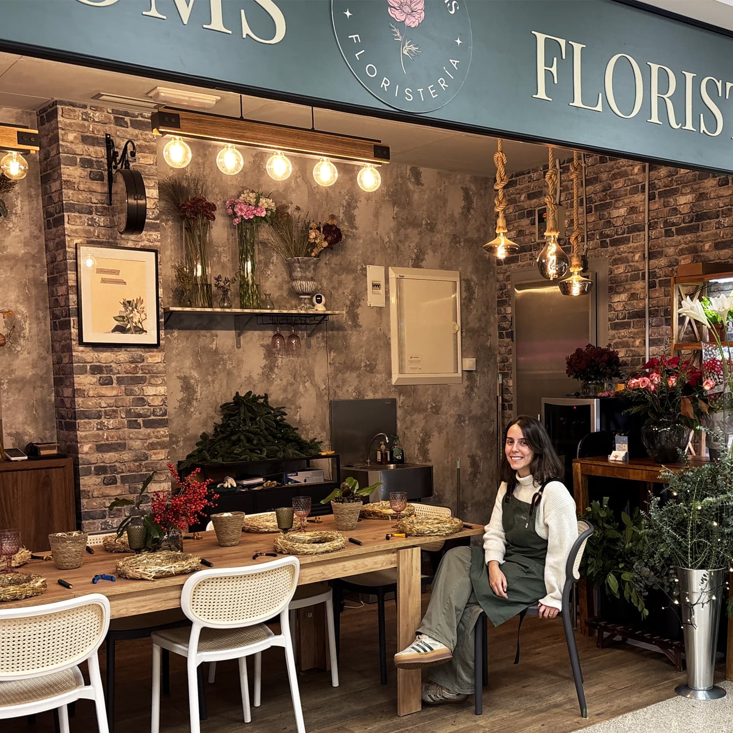 Mesa de madera totalmente acondicionada para 10 personas con materiales florales en el Mercado de Ibiza.