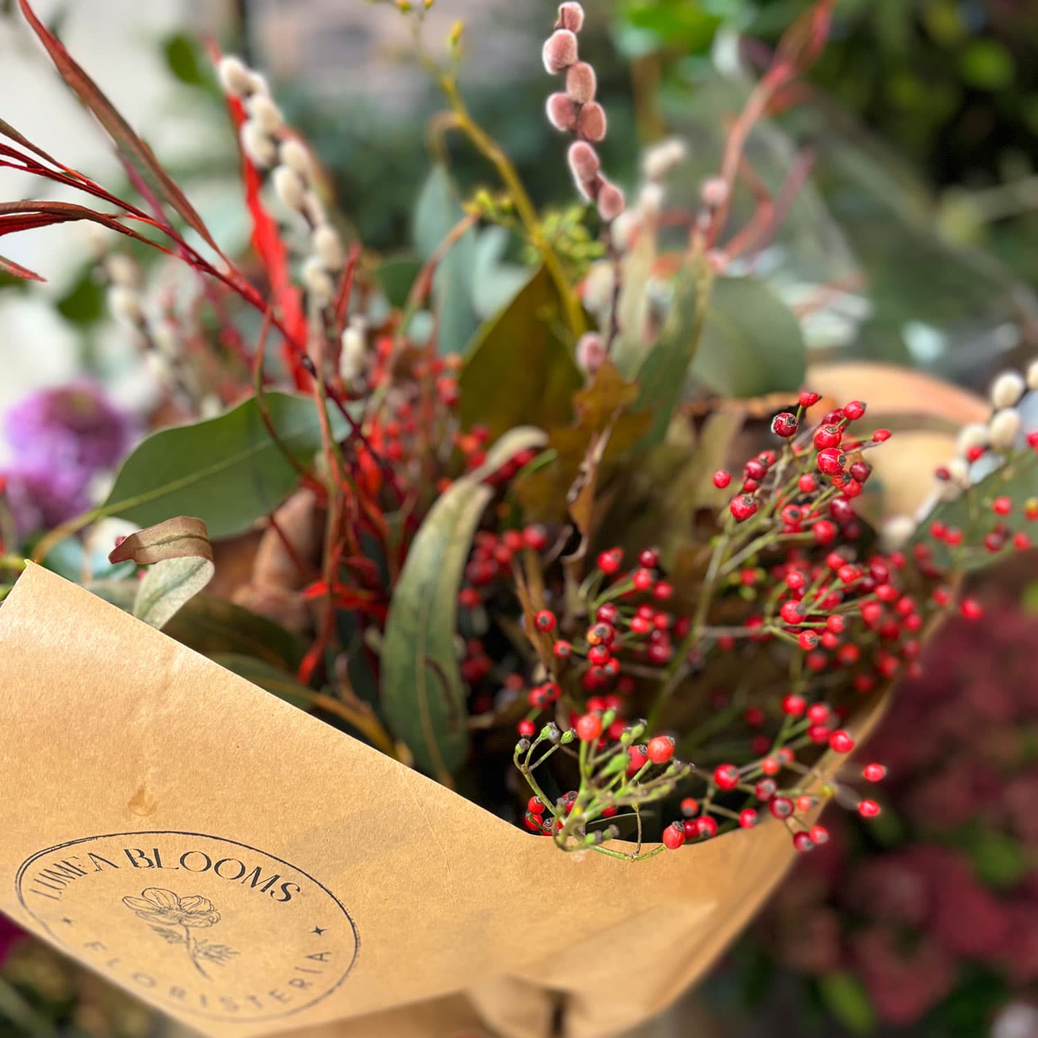 Detalle de ramificación silvestre con bayas de invierno, hojas de magnolio y brotes de sauce en ramo navideño